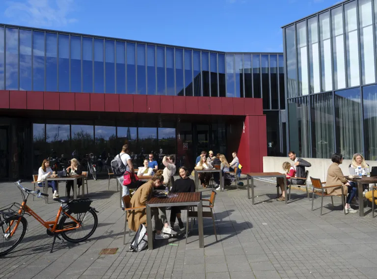 Fólk situr fyrir utan Háskólatorg á björtum og sólríkum degi