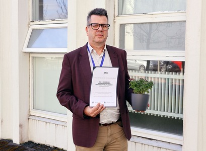Stefán Hrafn Jónsson, prófessor í félagsfræði heldur á viðurkenningu og plöntu