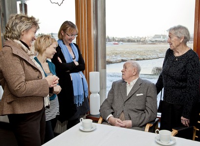 Bent Scheving Thorsteinsson sonur Bergþóru og Þorsteins Schevings Thorsteinssonar, situr við borð með kaffibolla á í Norræna húsinu og talar við 4 konur sem standa í kringum hann.